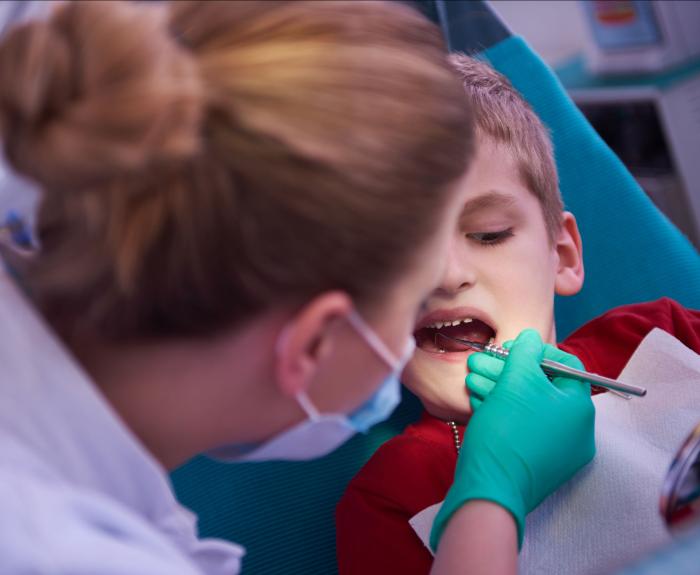 Dentist examining kid in dental chair